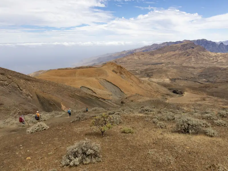 Wanderer auf einem Pfad in einer vulkanischen Landschaft.
