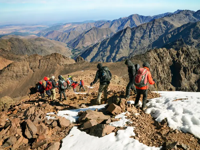 Wandergruppe im Atlasgebirge auf einem Bergpfad mit Schnee.