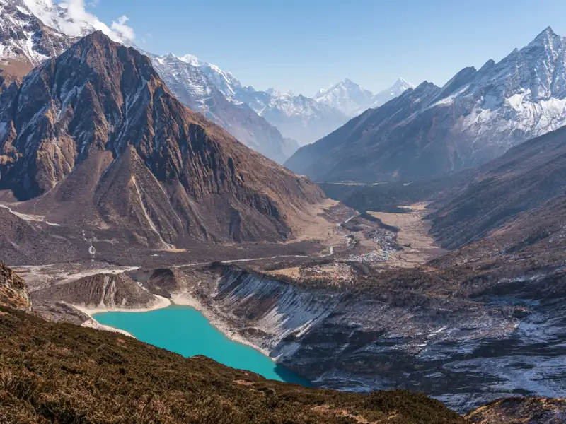 Türkisfarbener Bergsee im Himalaya, umgeben von schneebedeckten Gipfeln.