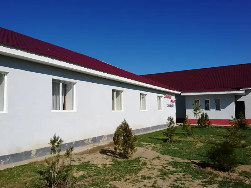 Außenansicht eines Gebäudes mit rotem Dach und weißen Wänden.