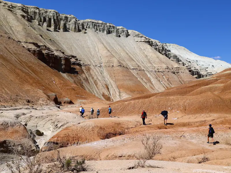 Wanderer auf einer Reise durchqueren eine rote Felslandschaft, die durch Erosion geformt wurde.