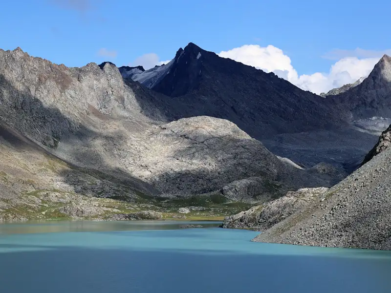 Türkisfarbener Bergsee umgeben von schroffen Gipfeln.