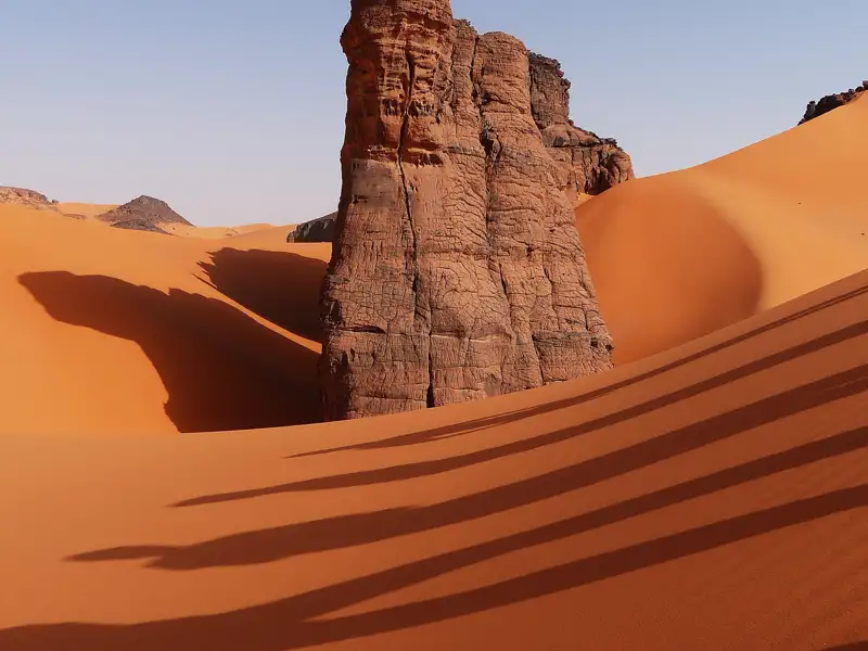 Felsformation und Sanddünen in der Wüste.