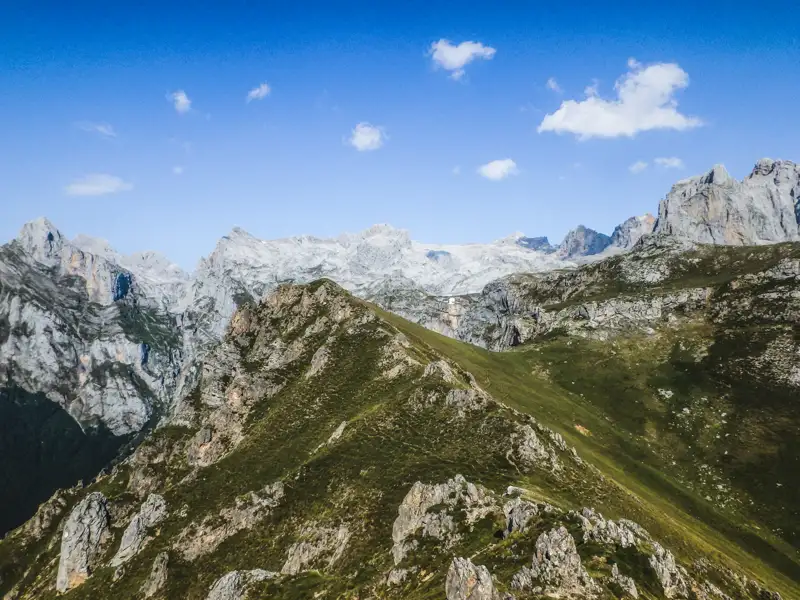 Berglandschaft mit grünen Hängen und felsigen Gipfeln.