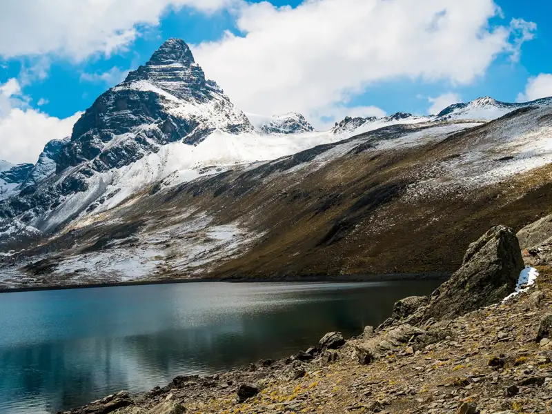 Ein ruhiger Bergsee am Fuße eines schneebedeckten Gipfels.