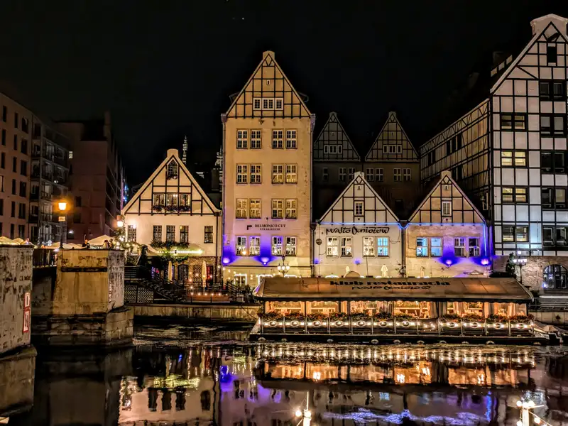 Historische Fachwerkhäuser am Kanal bei Nacht beleuchtet.