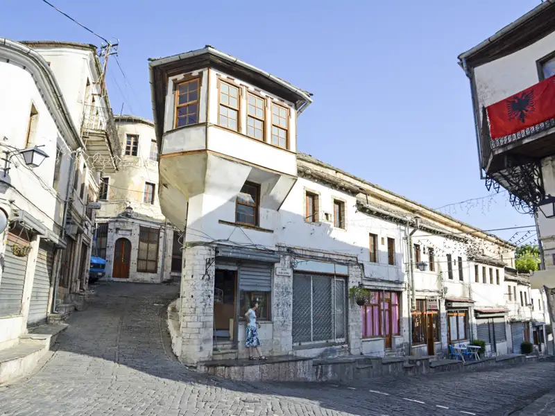 Szene einer Straße mit traditionellen albanischen Häusern, die die lokale Architektur zeigt.