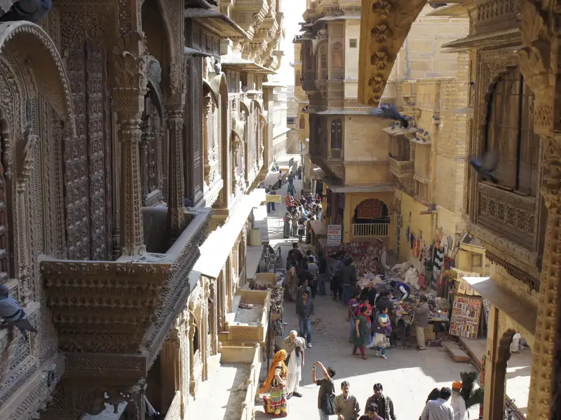 Eine belebte Straße mit traditionellen, verzierten Gebäuden und Händlern, die ihre Waren anbieten.