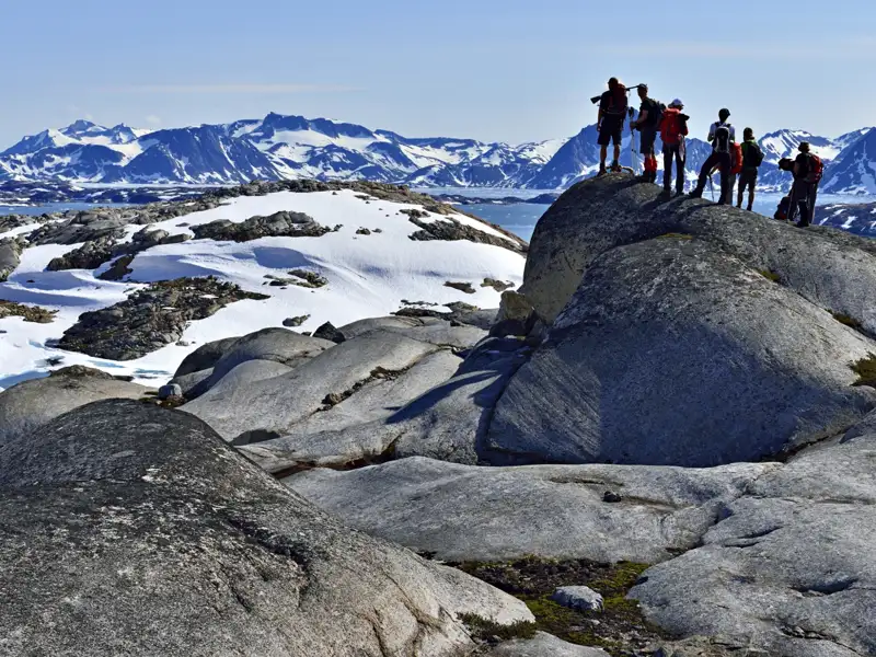 Farbenfrohe Häuser in einer Siedlung vor schneebedeckten Bergen.