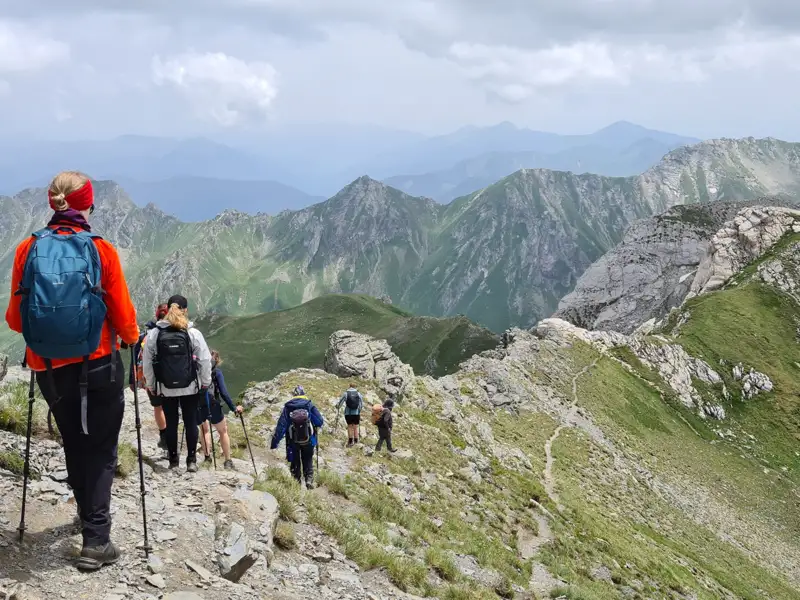 Wandergruppe auf einem Bergpfad inmitten einer Berglandschaft.