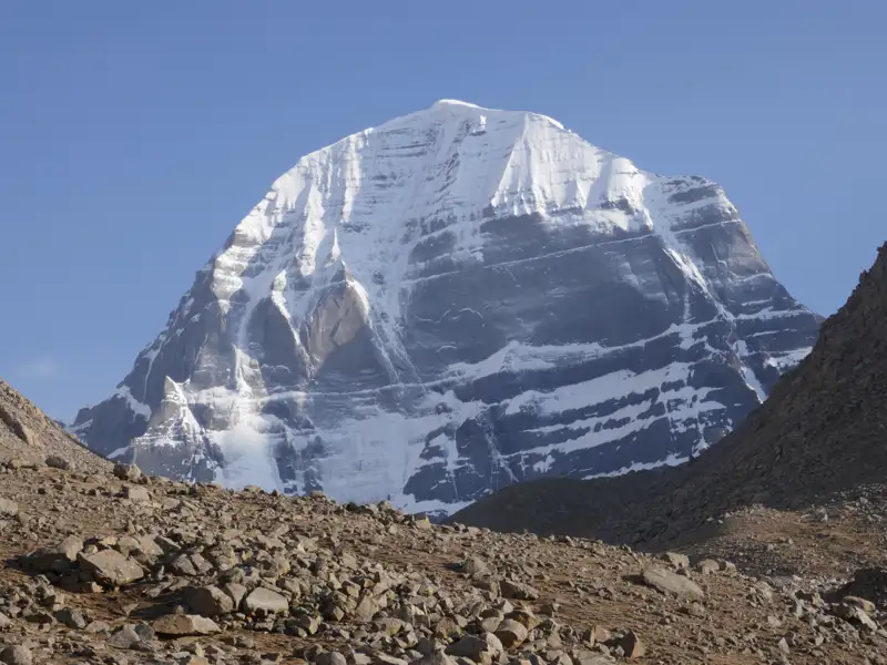 Der schneebedeckte Gipfel des heiligen Berges Kailash, umgeben von einem felsigen Gelände.