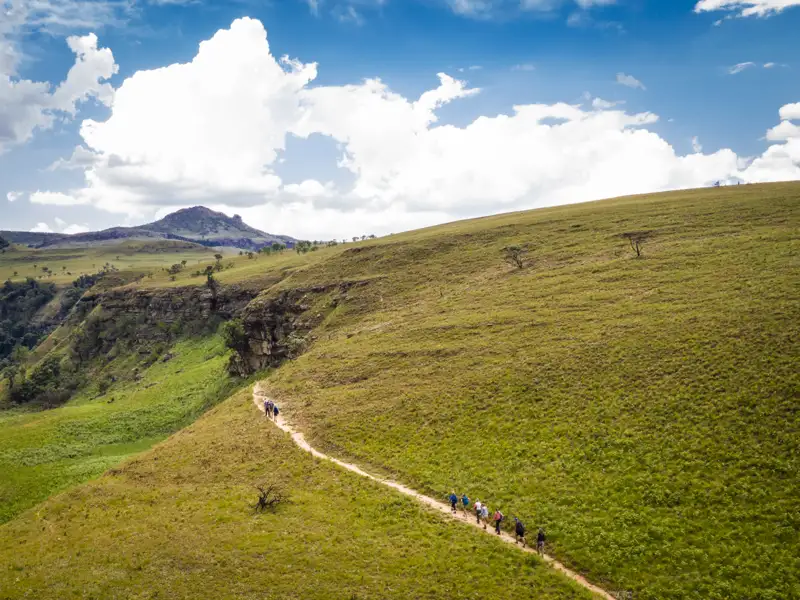 Wandergruppe auf einem Pfad in einer Hügellandschaft.
