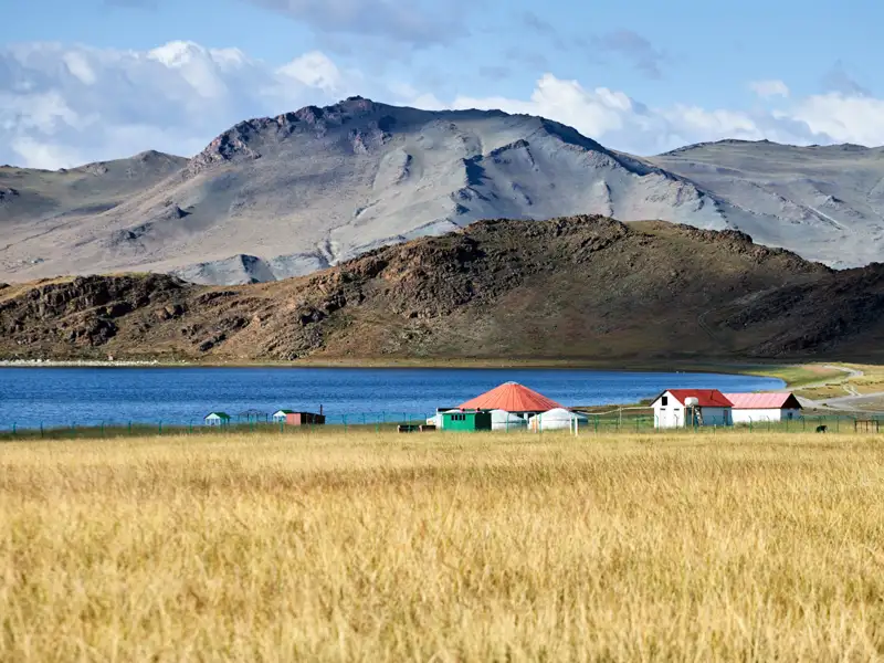 See mit Häusern und Bergen im Hintergrund.