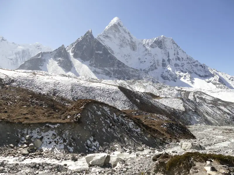 Schneebedeckte Bergkette mit Geröllfeld im Vordergrund.