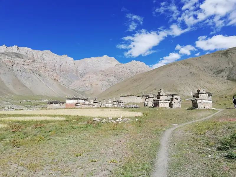 Historische Gebäude und Stupas in einem Gebirgstal.