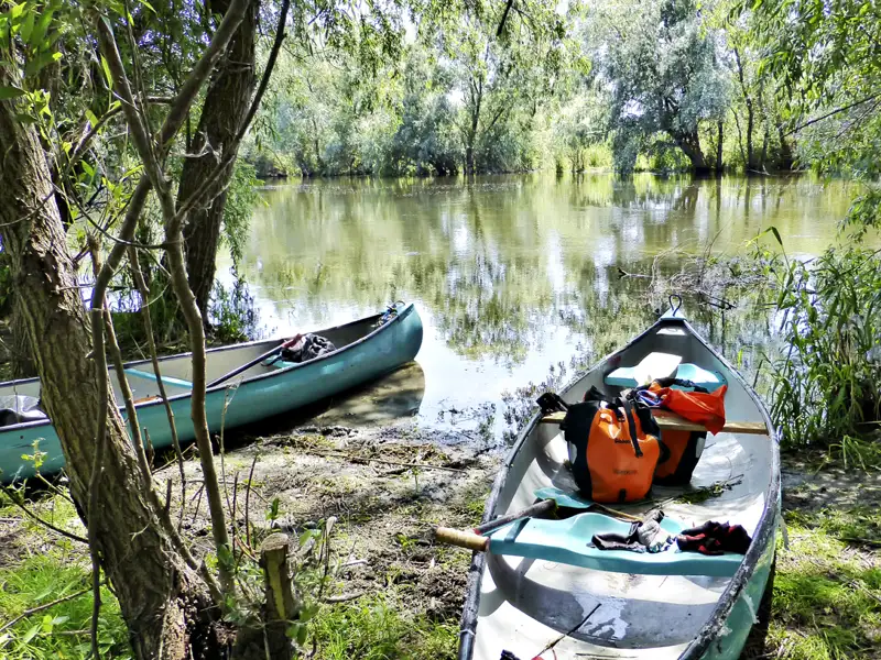 Zwei Kanus am Ufer eines Flusses, vorbereitet für eine Paddeltour.