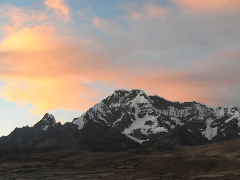 Schneebedeckte Gipfel einer Bergkette bei Sonnenuntergang.