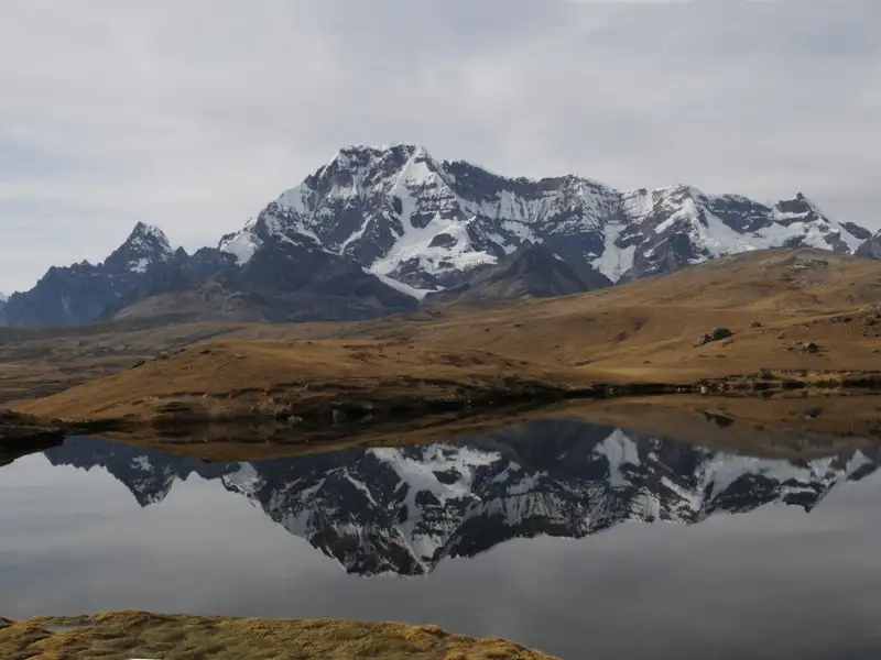 Spiegelbild eines schneebedeckten Berges in einem ruhigen Bergsee.