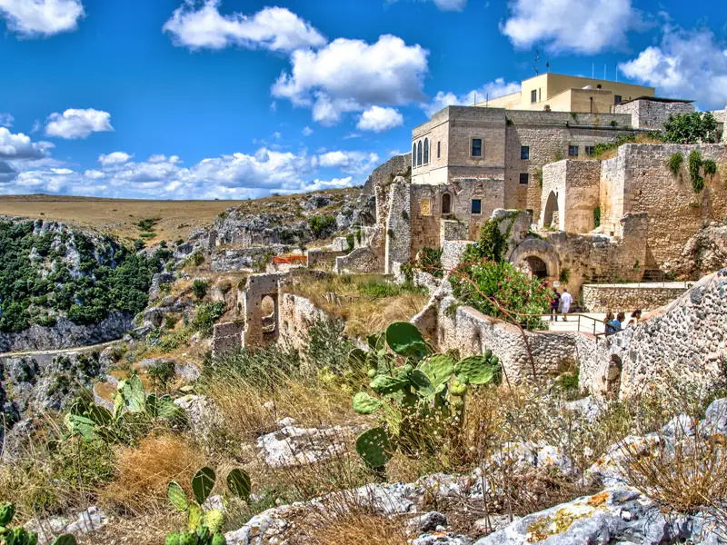 Historische Stätte mit Gebäuden und Ruinen in einer felsigen Umgebung.