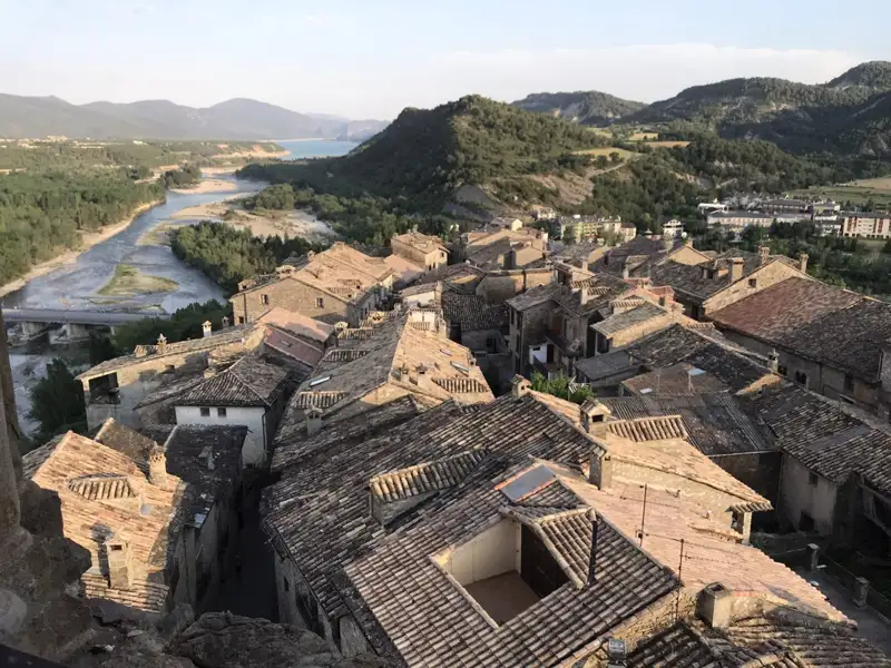 Panorama einer Stadt mit Blick auf die Dächer, einen Fluss und die umliegenden Berge.