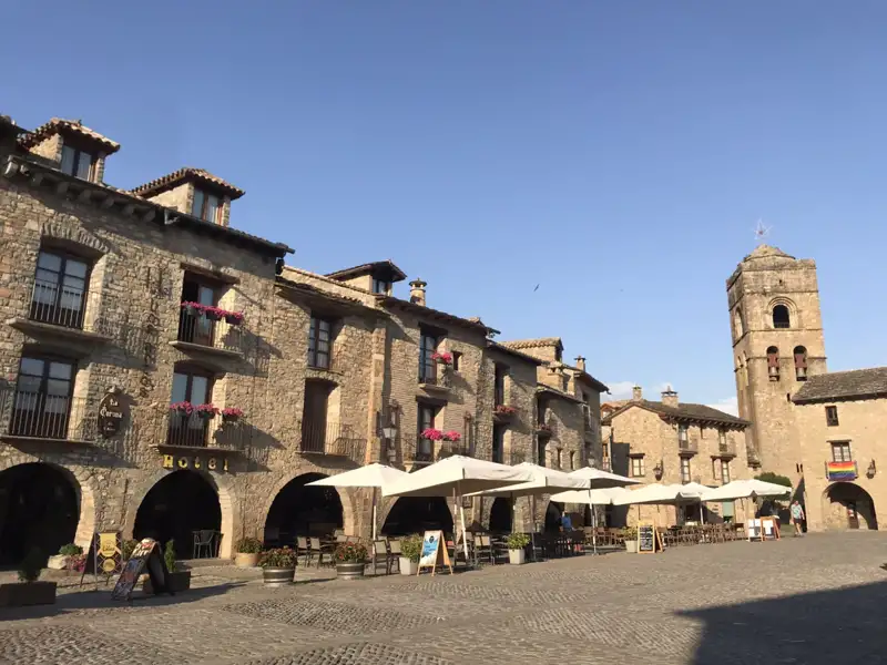 Marktplatz mit Steingebäuden und Kirchturm.
