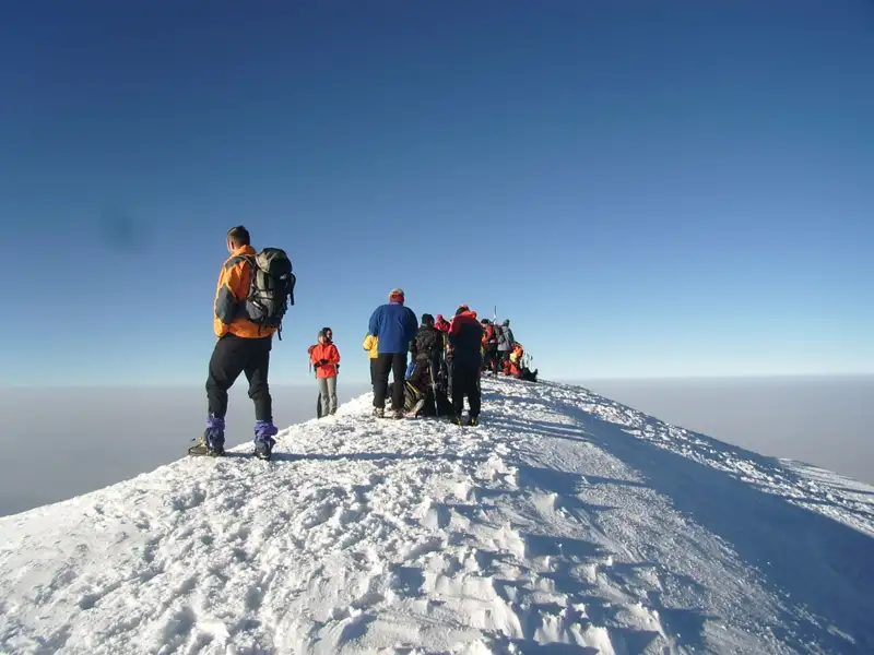 Wanderer erreichen den Gipfel eines schneebedeckten Berges.