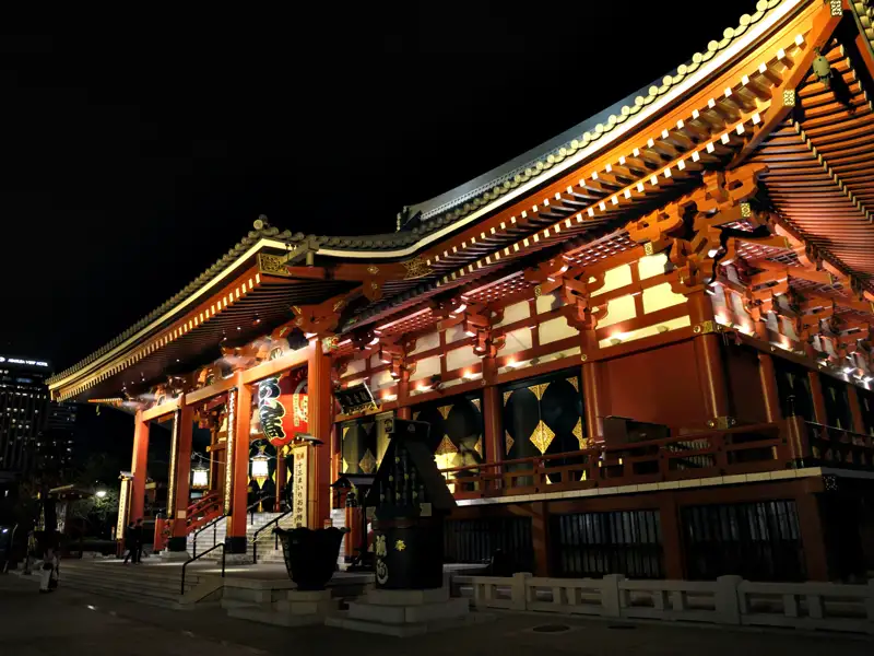 Beleuchteter japanischer Tempel bei Nacht.