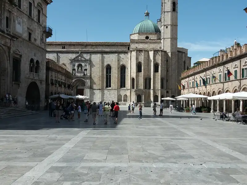 Blick auf die Piazza del Comune mit Besuchern und umliegenden Gebäuden.