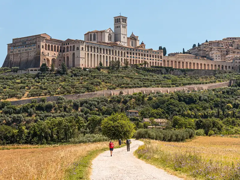 Wanderer auf einem Weg, der zur Basilika San Francesco in Assisi führt.