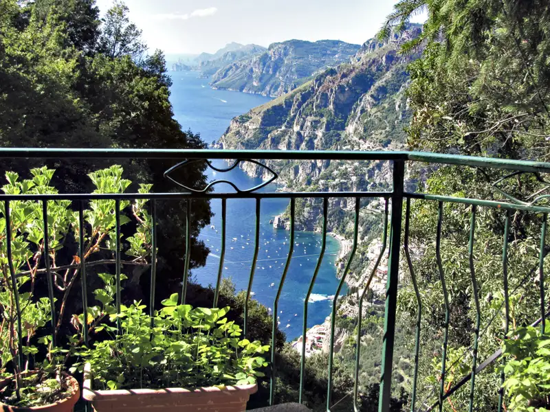 Ausblick von einem Balkon auf die Amalfiküste. Das Meer und die steilen Klippen sind im Hintergrund zu sehen.