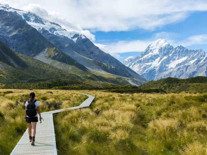 Wanderer auf einem Holzsteg in einer Berglandschaft.