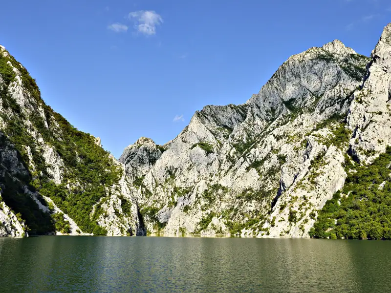 Panorama eines Sees, umgeben von felsigen Bergen.