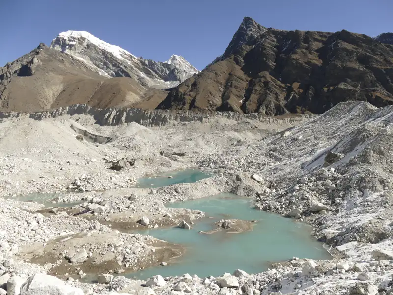 Türkisblaue Gletscherseen inmitten einer Hochgebirgslandschaft mit schneebedeckten Gipfeln im Hintergrund.