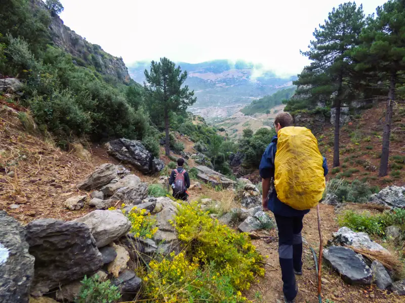 Zwei Wanderer auf einem Bergpfad mit Blick auf das Tal.