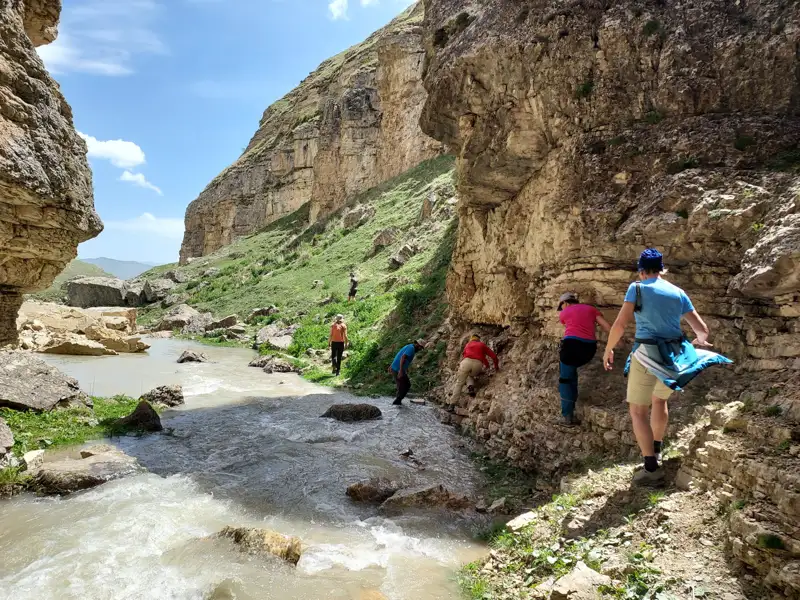 Wanderer auf einem Pfad entlang eines Flusses in einer Schlucht.