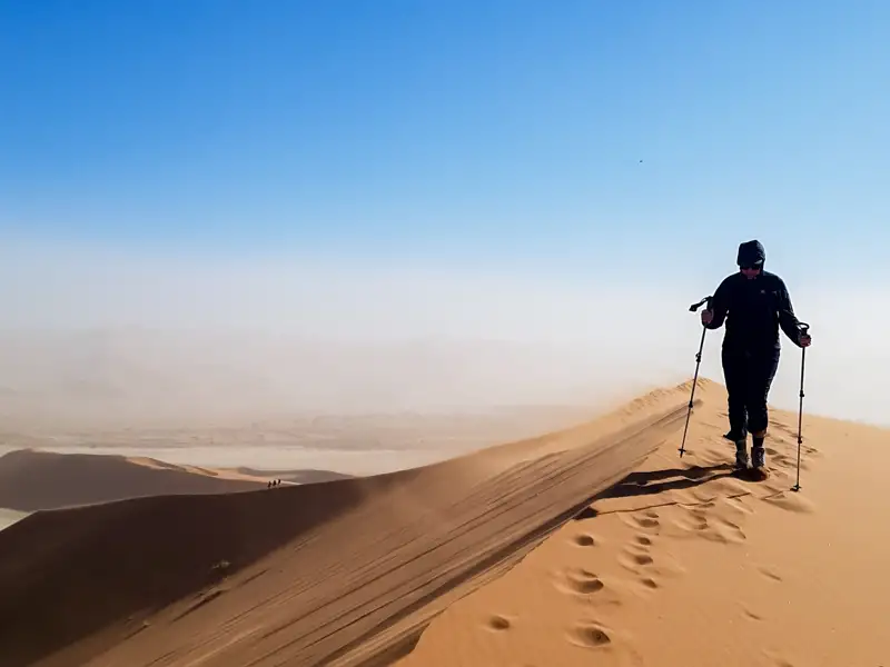 Wanderer mit Stöcken auf einer Düne.