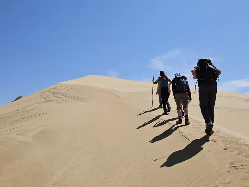 Wanderer besteigen eine Sanddüne während ihrer Reise.