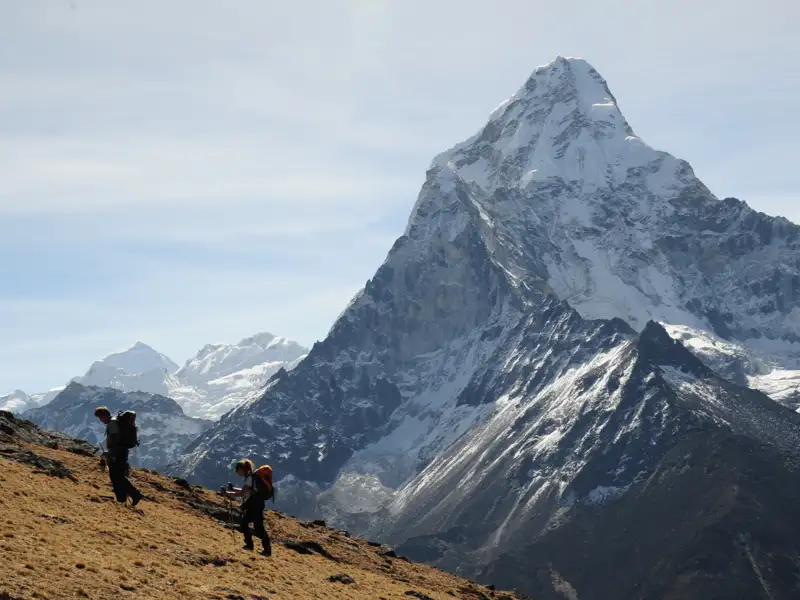 Wanderer auf einem Bergpfad, im Hintergrund ein schneebedeckter Berggipfel.