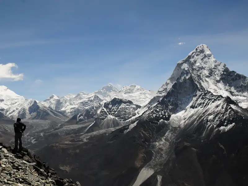 Panoramablick auf die schneebedeckten Gipfel des Himalaya mit einem Wanderer im Vordergrund.
