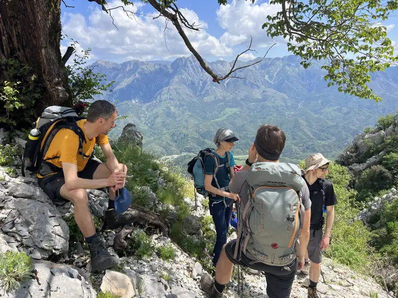 Wanderer machen eine Pause auf einem Bergpfad und genießen die Aussicht auf das Tal und die Bergkette.
