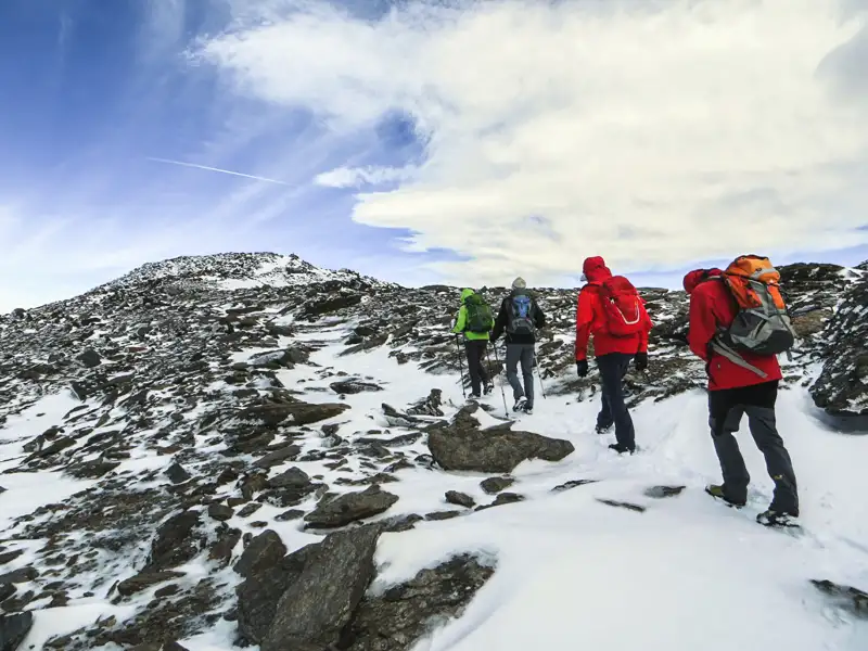 Wanderer auf einem schneebedeckten Bergpfad.
