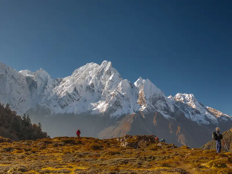 Wanderer auf einem Bergpfad mit Blick auf die schneebedeckten Gipfel.