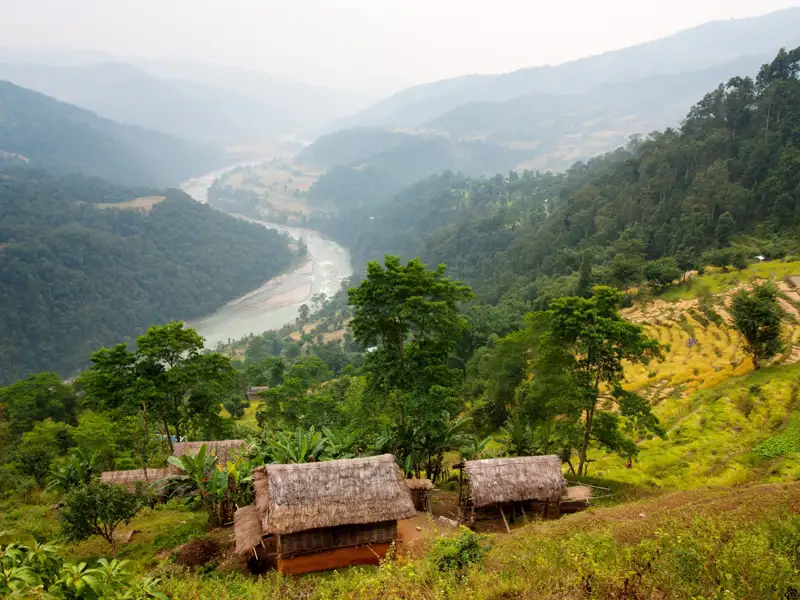 Traditionelle Hütten mit Blick auf Reisterrassen und einen Fluss im Tal.
