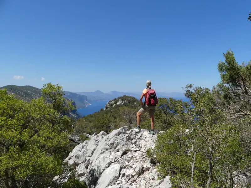 Wanderer auf einem felsigen Gipfel mit Blick auf die Küste.
