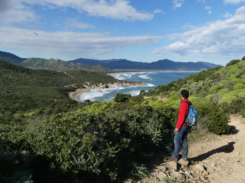 Wanderer auf einem Küstenpfad mit Blick auf das Meer und die Berge.