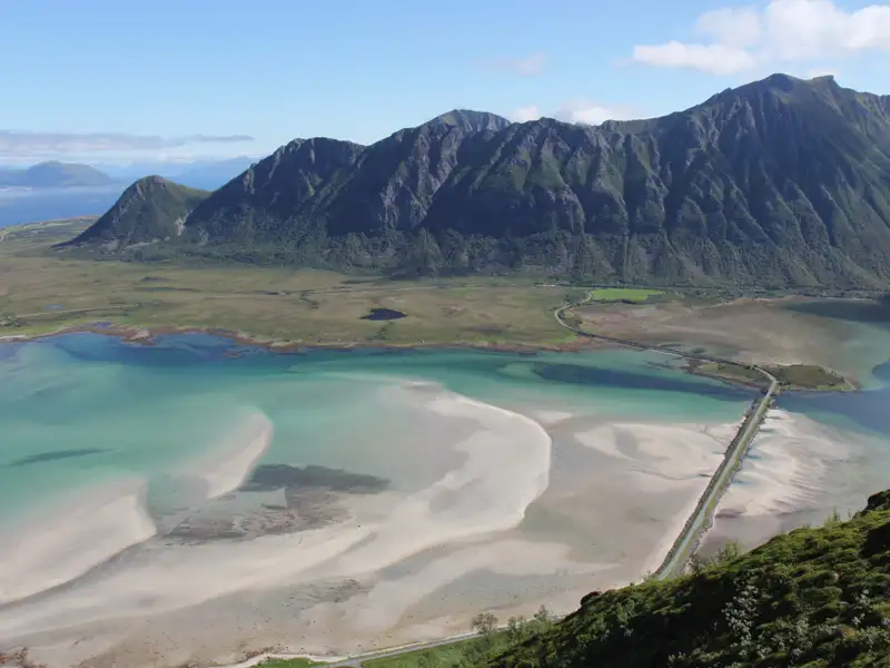 Panoramablick auf die Küstenregion mit türkisfarbenem Wasser, Sandbänken und Bergen im Hintergrund.