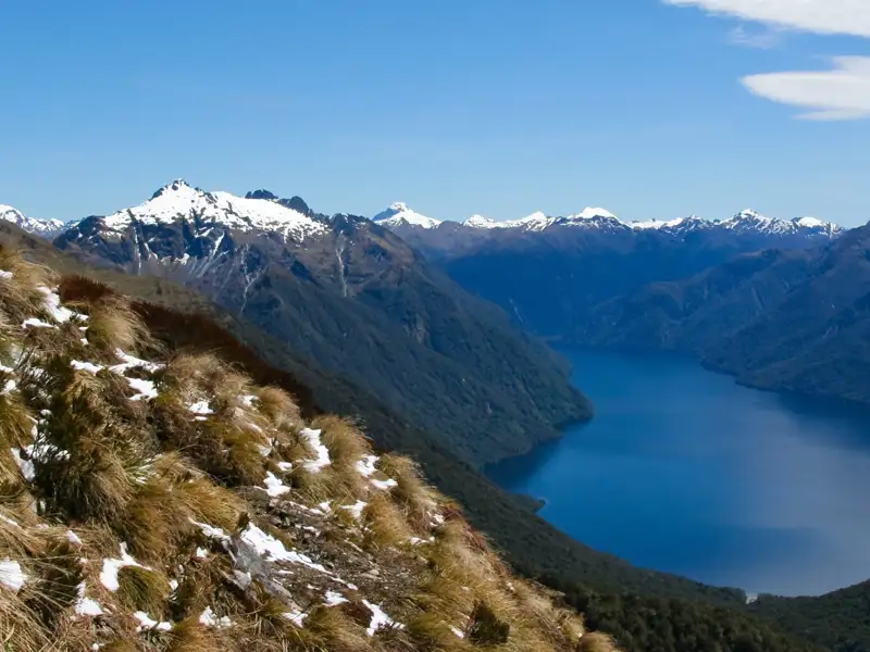 Panoramablick auf einen Bergsee und schneebedeckte Gipfel.
