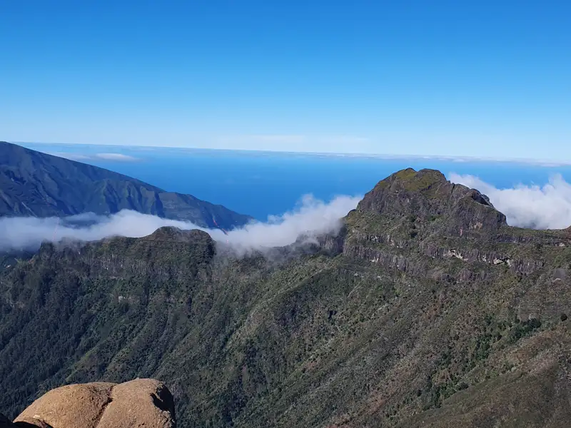 Blick über die Berglandschaft mit Wolkenformationen und Meer.