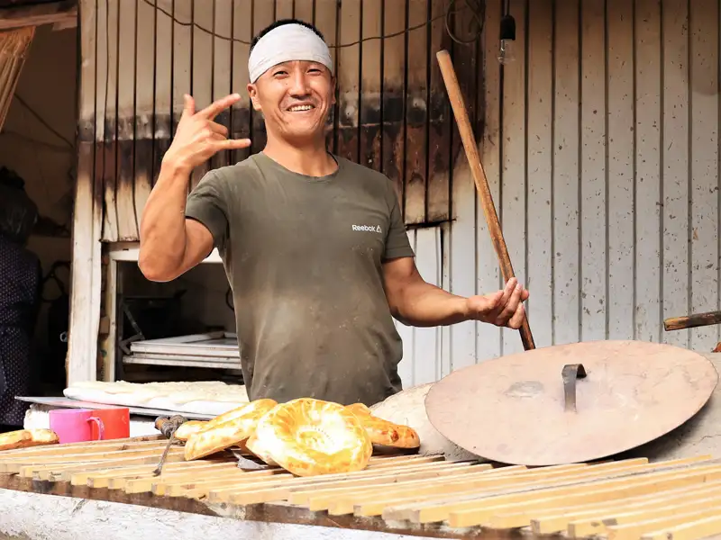 Bäcker präsentiert Fladenbrot an seinem Stand.