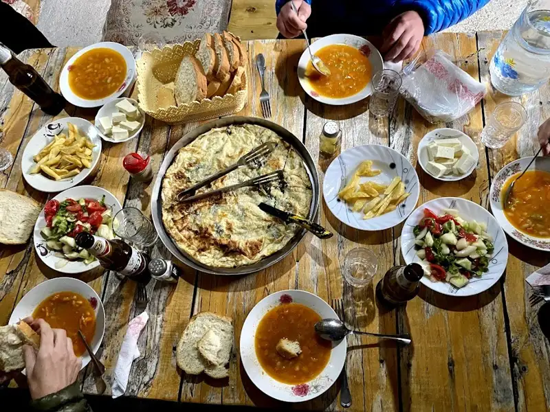 Gemeinsames Essen während der Reise: Suppe, Salat, Brot, Pommes und Omelett auf einem Holztisch.